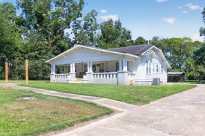 A white single-story house with a porch, a small attached garage, and a well-maintained lawn. - Cozy Aberdeen MS Retreat Near Lake & MSU (Aberdeen)