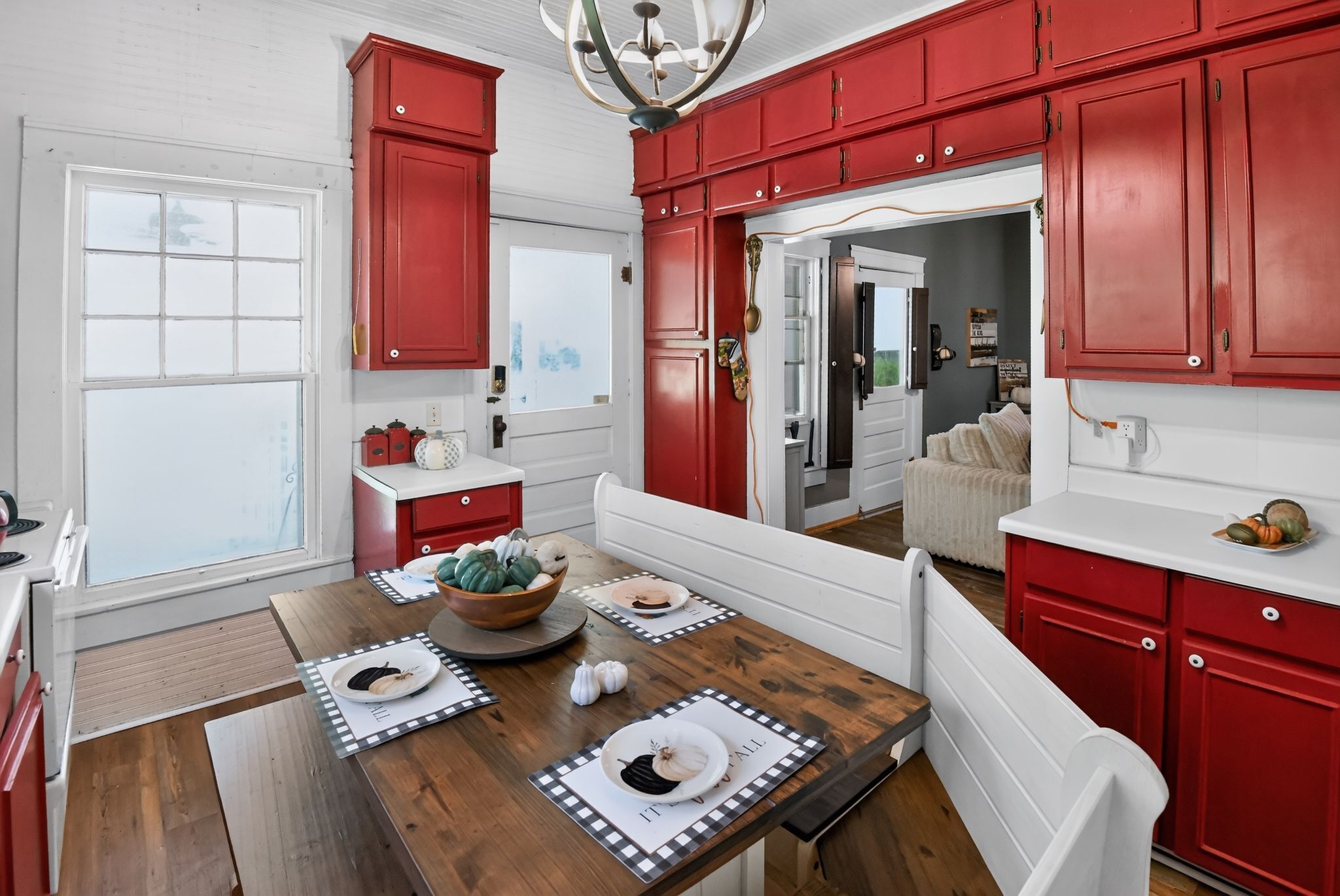 Una cocina con armarios rojos, una mesa de comedor de madera y vista al área de estar.