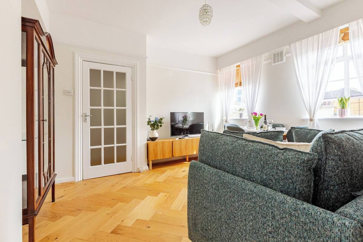 A living room with a sofa, TV, wooden cabinet, and a door with glass panels.