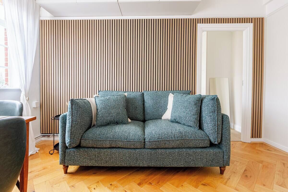Un salon avec un canapé, un fauteuil, un radiateur et une porte.
