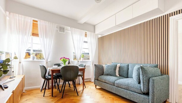 Una sala moderna con sofá, mesa de comedor, sillas y piso de madera.