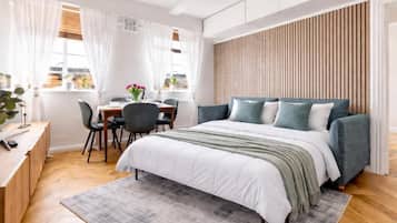 A modern bedroom with a bed, desk, and chair, a window with curtains, and a wooden panel wall.