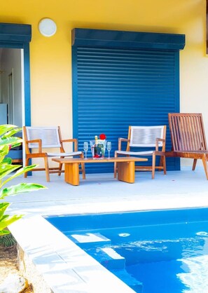 A poolside area with a table, chairs, and a bottle of champagne. - Amazonia: Central, quiet three-bedroom apartment with a private pool (Les Abymes)