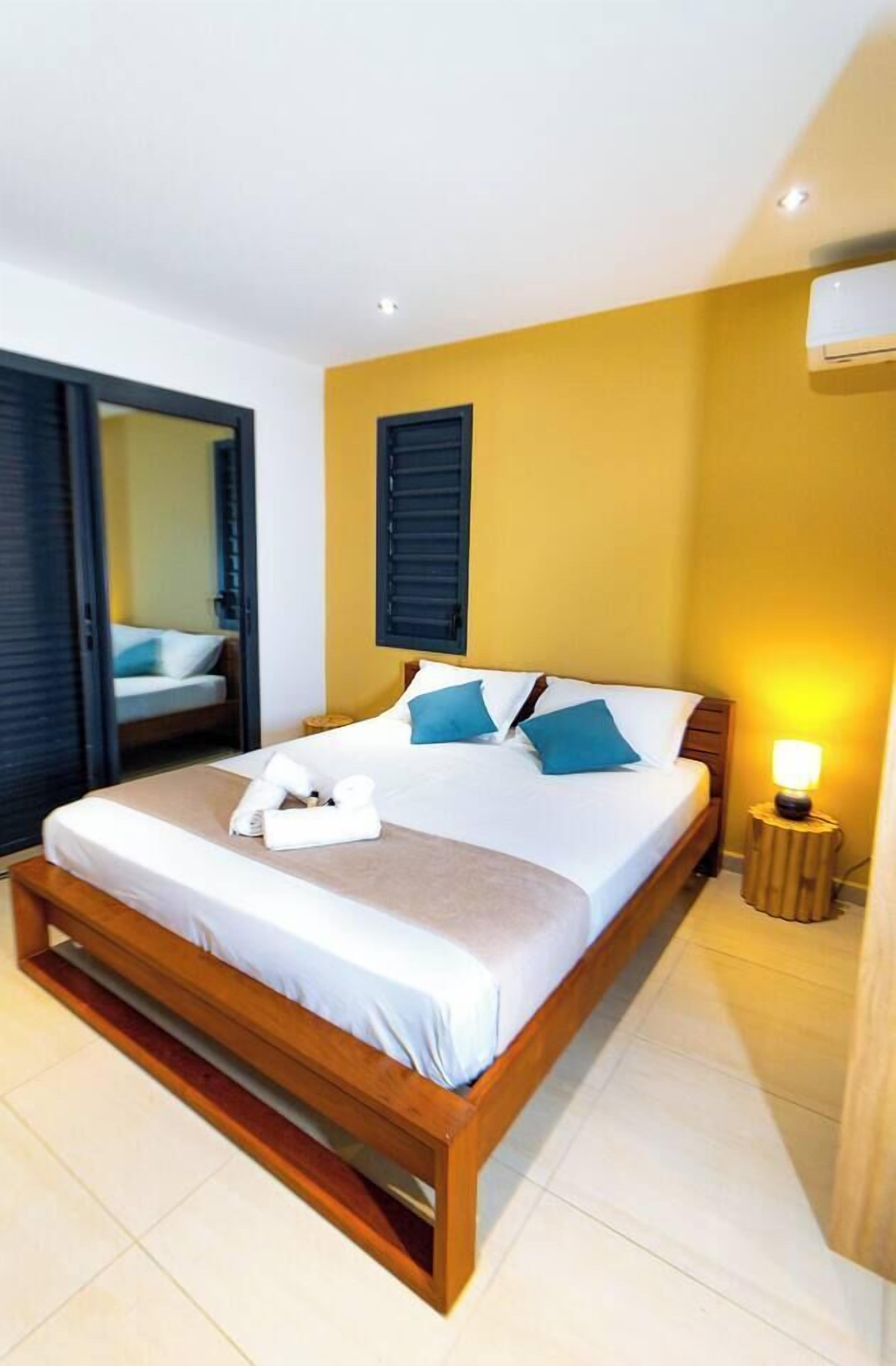 A hotel room with a bed, a bedside lamp, and a window with blinds.