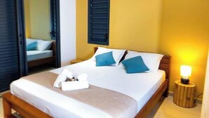 Una habitación de hotel con cama, lámpara de noche y ventana con persianas.