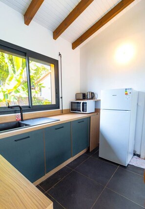 A compact kitchen with a sink, microwave, and refrigerator. - Amazonia: Central, quiet three-bedroom apartment with a private pool (Les Abymes)