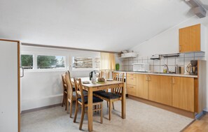 A compact kitchen with wooden cabinets, a dining table with chairs, and a view through the window. - 2 bedroom nice apartment in Ringkøbing (Ringkøbing)