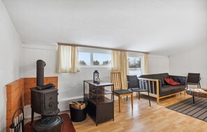 A cozy living room with a fireplace, a sofa, a table, and a chair. - 2 bedroom nice apartment in Ringkøbing (Ringkøbing)