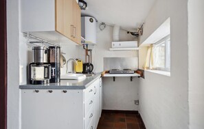 Eine kleine Küche mit Spüle, Wasserkocher und Kaffeemaschine.
