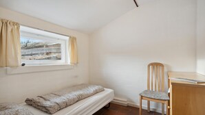 A small, single-bed room with a window, a wooden chair, and a desk. - Stunning apartment in Ringkøbing with WiFi (Ringkøbing)