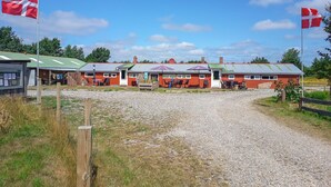 A building with a gravel driveway, outdoor seating area, and a flagpole. - Cozy home in Ringkøbing with WiFi (Ringkøbing)
