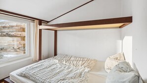 A bedroom with a bunk bed, a window with a view of a wooden structure, and a headboard with a light fixture. - Cozy home in Ringkøbing with WiFi (Ringkøbing)