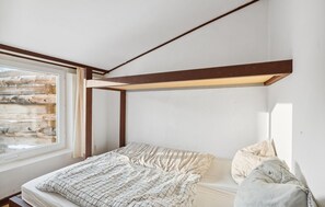 A bedroom with a bunk bed, a window with a view of a wooden structure, and a headboard with a light fixture. - Cozy home in Ringkøbing with WiFi (Ringkøbing)