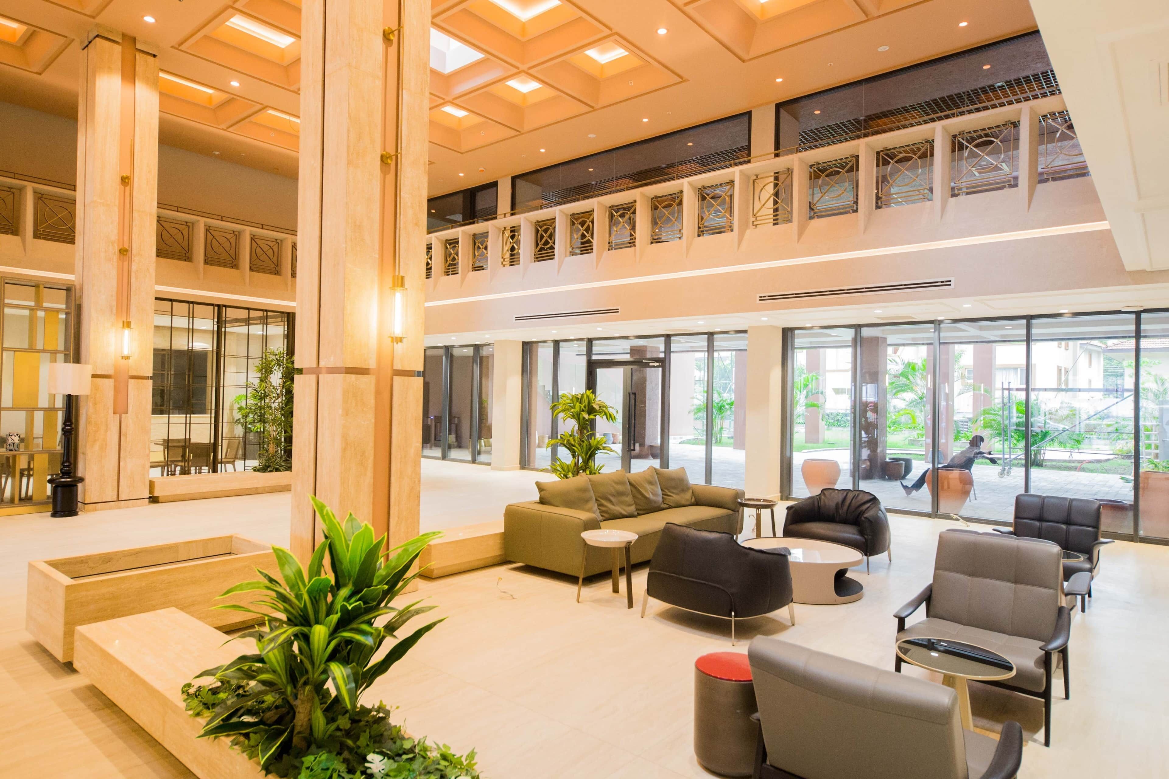 A spacious lobby with a high ceiling, large windows, and a seating area with sofas and chairs.