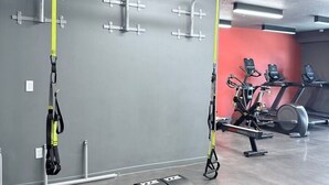 Ett gym med träningsutrustning, inklusive en stång för chins och en motionscykel.