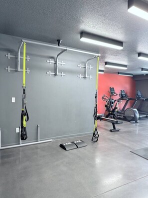 Ein Fitnessraum mit Trainingsgeräten, darunter eine Klimmzugstange und ein Ergometer.