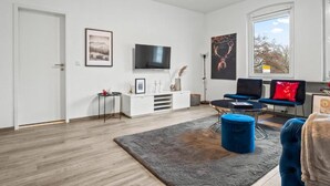 A modern living room with a flat-screen TV, a fireplace, a sofa, and a coffee table. - Apartmenthaus VINA -  Smart Urban Stay (Kassel)