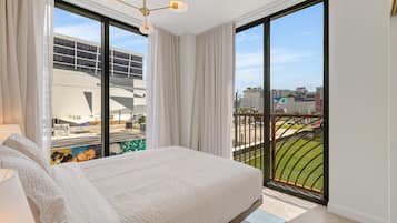 Quarto com uma cama grande, vista para a cidade e varanda com corrimão.