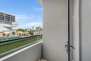 A view from a balcony with a clear sky, a modern building, and a street with parked cars. - Miami Oasis 2BR Apartment with Pool (Miami)