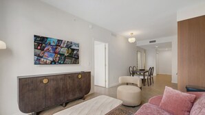 Una sala moderna con un mueble bajo de madera oscura, un sofá beige, una mesa de centro y un cartel de película colgado en la pared.