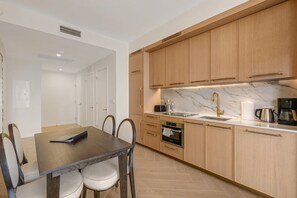 A modern kitchen with wooden cabinets, a marble countertop, and a built-in oven. - Miami Oasis 2BR Apartment with Pool (Miami)