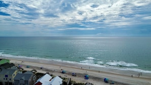 A beach with a clear sky, calm sea, and buildings in the foreground. - 4BR in Downtown Surf City • 1 Block to Beach (Surf City)
