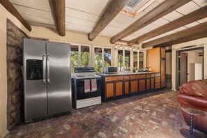 Eine Küche mit einem Edelstahl-Kühlschrank, einem Herd und einer Mikrowelle. Es gibt einen Holzkasten und eine Kaffeebar.