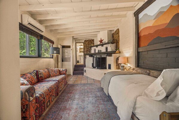 A room with a sofa, a bed, a fireplace, and a mural on the wall.