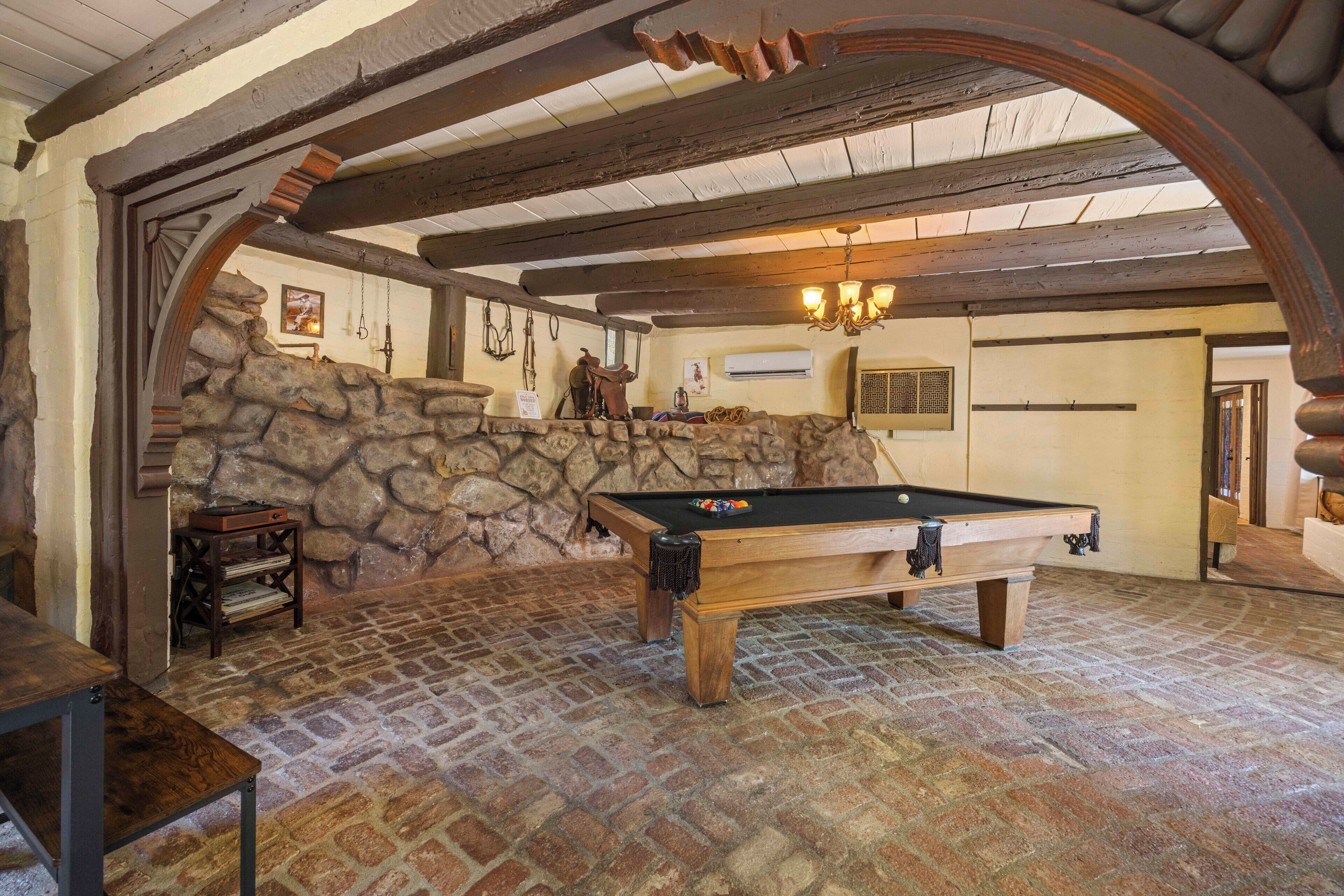 A billiards table in a room with stone walls and wooden beams.