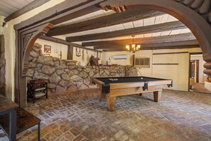 Ein Billardtisch in einem Raum mit Steinwänden und Holzbalken.