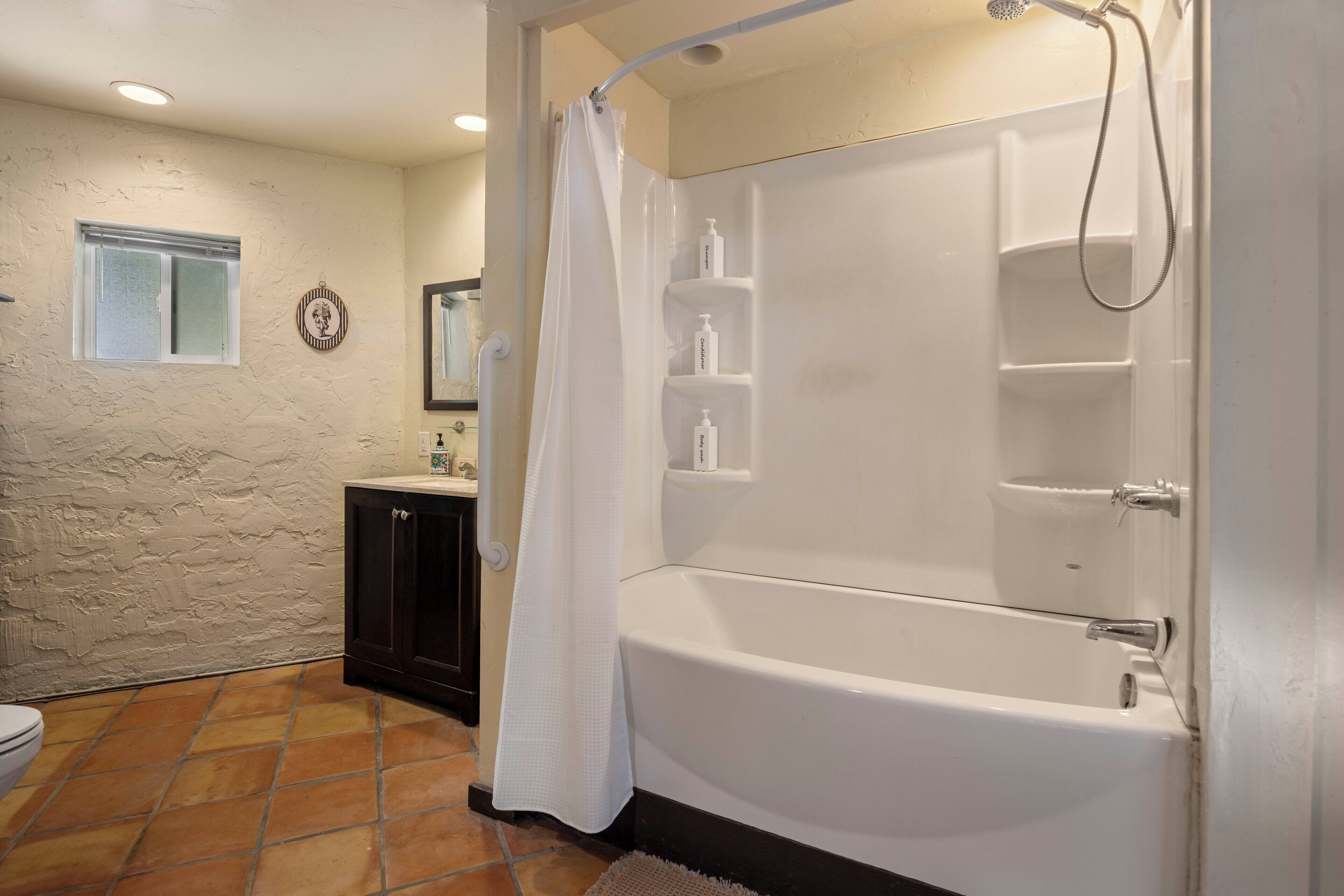 Une salle de bain équipée d’une baignoire, d’une douche et d’un meuble-lavabo avec un miroir.