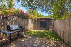 A backyard with a barbecue grill, a wooden fence, and a sign that reads 'HOWDY FAM'.