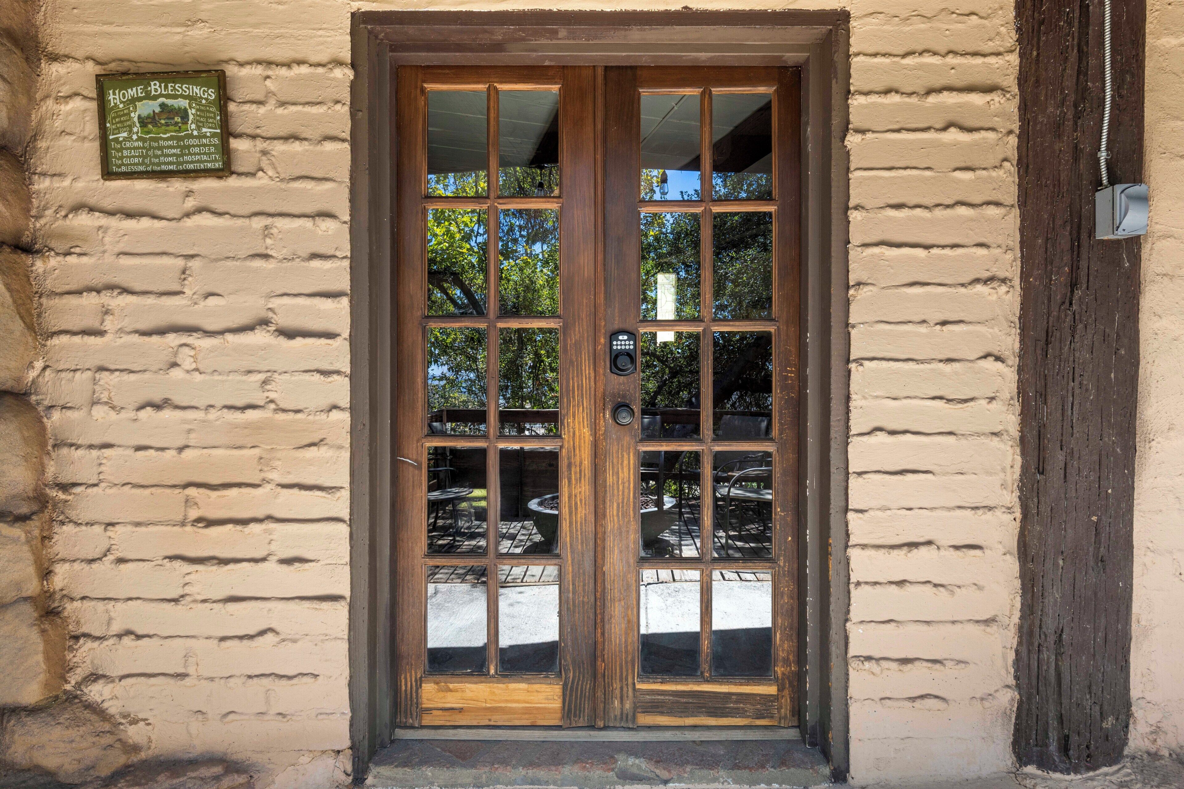 A wooden door with a glass panel, a plaque above it, and a brick wall.