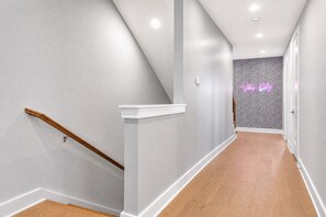 A modern interior with a wooden staircase, a white wall, and a patterned wall in the distance. - 4BR Nashville house sleeps 12, minutes to Broadway & downtown (Nashville)