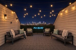 Ett utomhusområde med sittplatser, bestående av två soffor och en neonskylt med texten ”Music City USA”, med en stadsbild i bakgrunden.