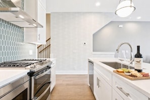 A modern kitchen with stainless steel appliances, a white countertop, and a wine bottle on the sink. - Rooftop deck townhome sleeps 12, minutes to Broadway, Nashville (Nashville)