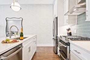 A modern kitchen with stainless steel appliances, a wine bottle, and a fruit platter on the counter. - Rooftop deck townhome sleeps 12, minutes to Broadway, Nashville (Nashville)