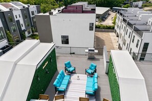 A rooftop terrace with a seating area, a barbecue grill, and a view of adjacent buildings. - 2 rooftop homes near Broadway & Geodis Park, sleeps 24 (Nashville)
