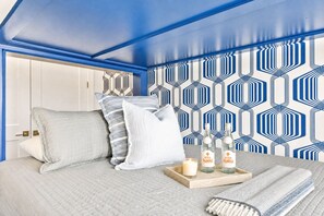 A bedroom with a bed, pillows, a tray with bottles, a candle, and a blanket. - 2 rooftop homes near Broadway & Geodis Park, sleeps 24 (Nashville)