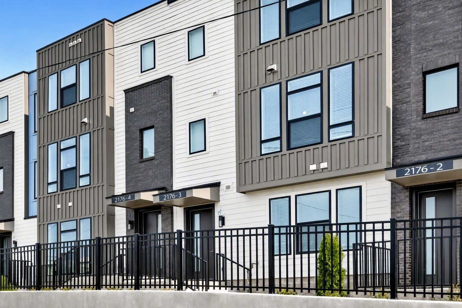A multi-story residential building with numbered balconies and a black metal fence.