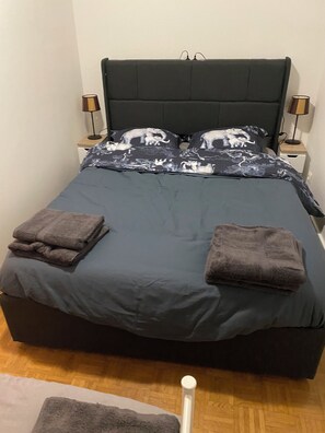 A bed with a dark headboard, two bedside lamps, and a patterned bedspread. - Chambord 9ET1 (Louvres)
