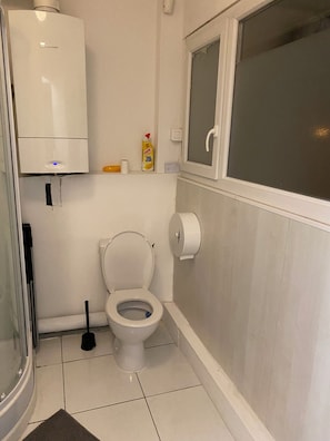 A bathroom with a toilet, a hand dryer, a hand soap dispenser, and a window. - Chambord 9ET1 (Louvres)