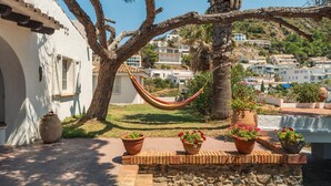 Edifici blanc amb cadira espanyola, plantes en testos i vista d'una comunitat situada en un turó.