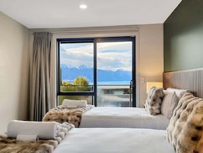 A hotel room with two beds, a large window with a mountain view, and a balcony. - Queenstown 3-Bed Getaway | Alpine Views (Queenstown)