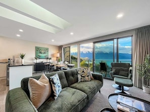 A modern living room with a sofa, armchairs, and a dining area. - Queenstown 3-Bed Getaway | Alpine Views (Queenstown)