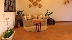 A living room with a sofa, a round table, and several potted plants. - Casa Espiral (San Miguel de Allende)