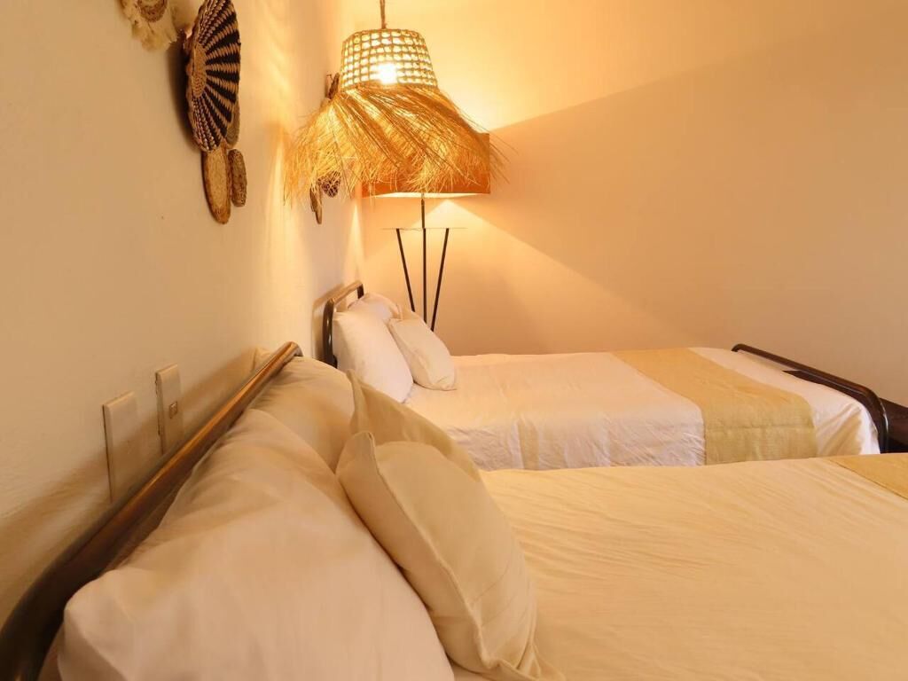Habitación de hotel con dos camas, una lámpara de noche y un adorno en la pared.