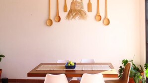 A dining area with a wooden table, white chairs, and a hanging light fixture. - Casa Espiral (San Miguel de Allende)