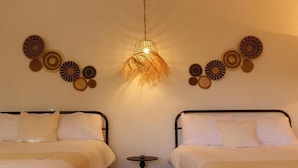 A room with two beds, a hanging light fixture, and wall decor. - Casa Espiral (San Miguel de Allende)