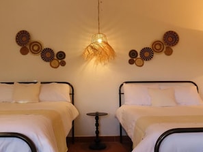 Quarto com duas camas, luminária pendente e decoração nas paredes.